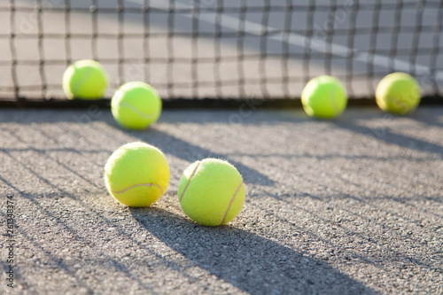 Six tennis balls by net on tennis court. Concept of workout, summer sports activities and playing outdoors.