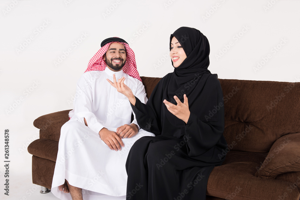 Arab couple enjoying and laughting while sitting on sofa chair at home Arab couple enjoying and laughting while sitting on sofa chair at home