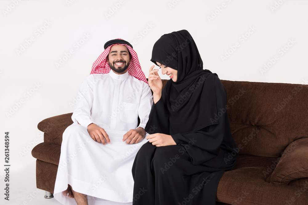 Arab couple enjoying and laughting while sitting on sofa chair at home