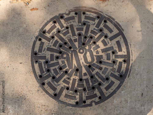 Manhole cover on pavement with patterns. Thailand.