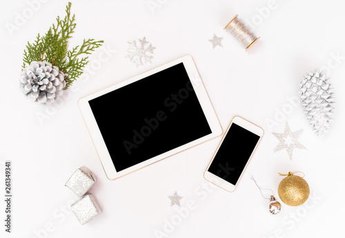 Computer laptop mobile display on table with isolated white screen for mockup in Christmas time. Christmas tree, gifts, decorations in background.