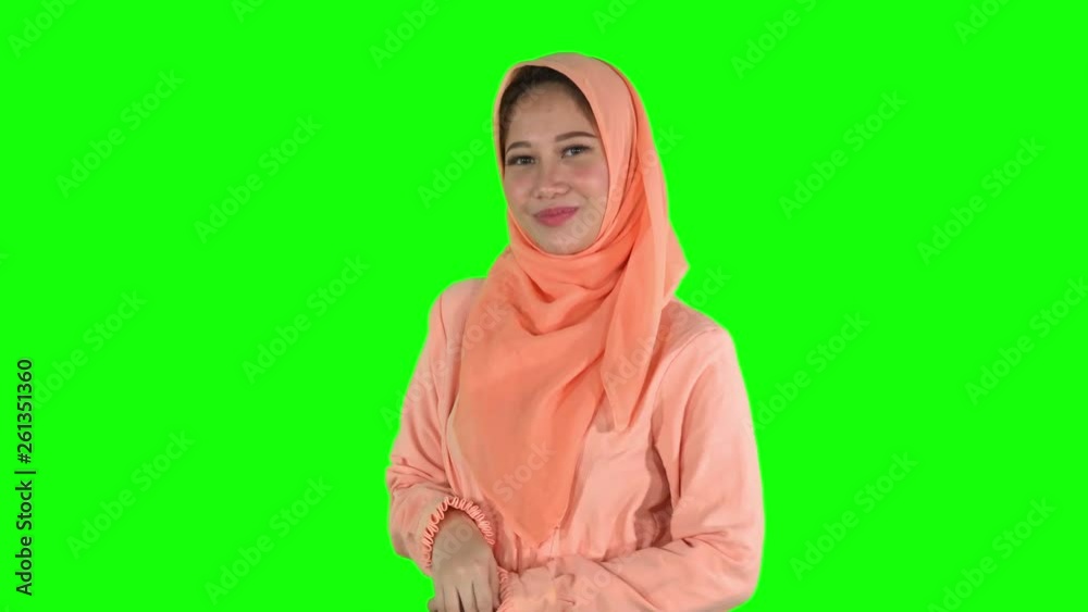 Cute young female muslim model smiling and posing at the camera in the studio while wearing islamic clothes. Shot in 4k resolution with green screen background Cute young female muslim model smiling and posing at the camera in the studio while wearing islamic clothes. Shot in 4k resolution with green screen background