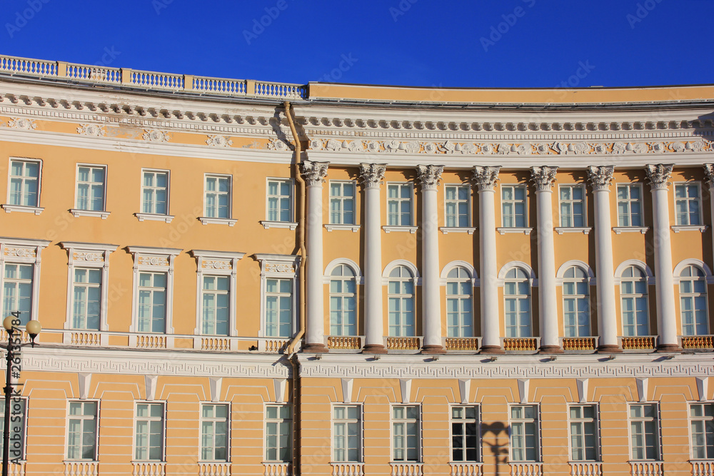 Historic building of yellow and white color with ornamental facade decor, classic pillars and symmetrical windows 