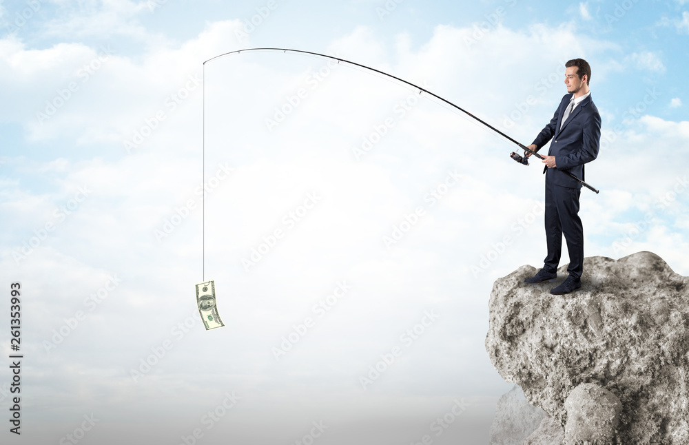 Elegant young businessman fishing cash from a huge rock