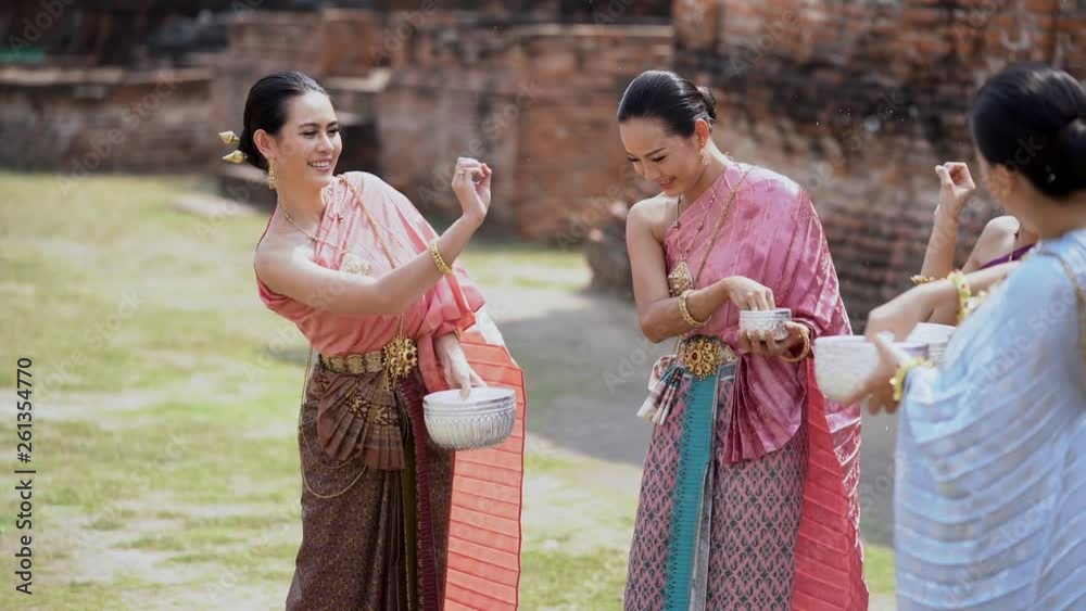 Songkran festival in Thailand. Happy Thai girls in Thailand cultural costume play water in the Thai new year festival called Songkran day. (Slow motion video)