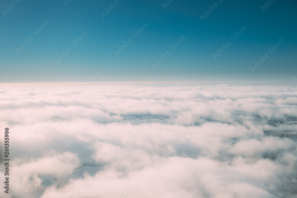 Beautiful Aerial View Of Sunny Clear Sky Over White Fluffy Clouds From Height Flight Of Plane. Bright White And Blue Colors Of Sunny Sky Beautiful Aerial View Of Sunny Clear Sky Over White Fluffy Clouds From Height Flight Of Plane. Bright White And Blue Colors Of Sunny Sky
