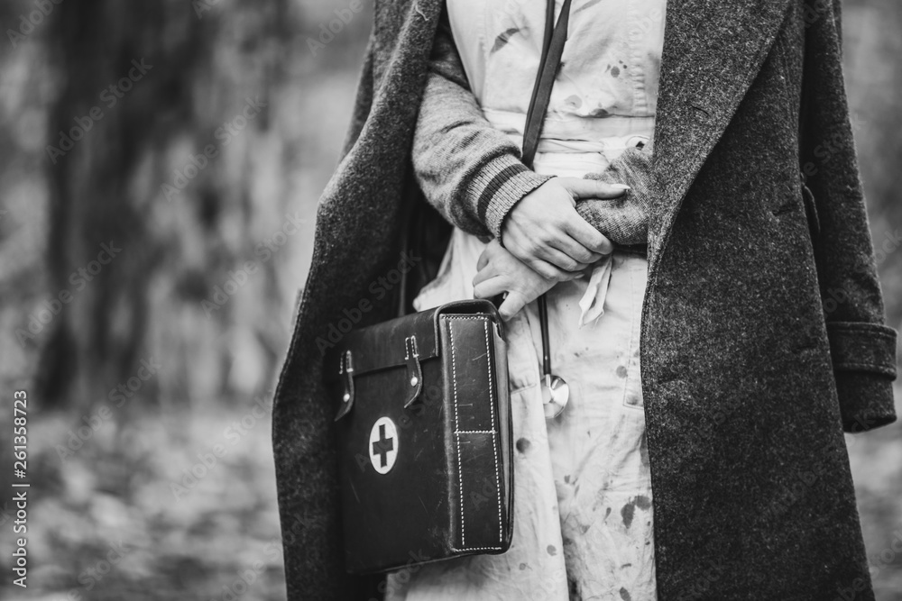 Re-enactor Wears Historical German Nurse Paramedic Of World War II Uniform With First Aid Kit. Photo In Black And White Colors. WWII WW2