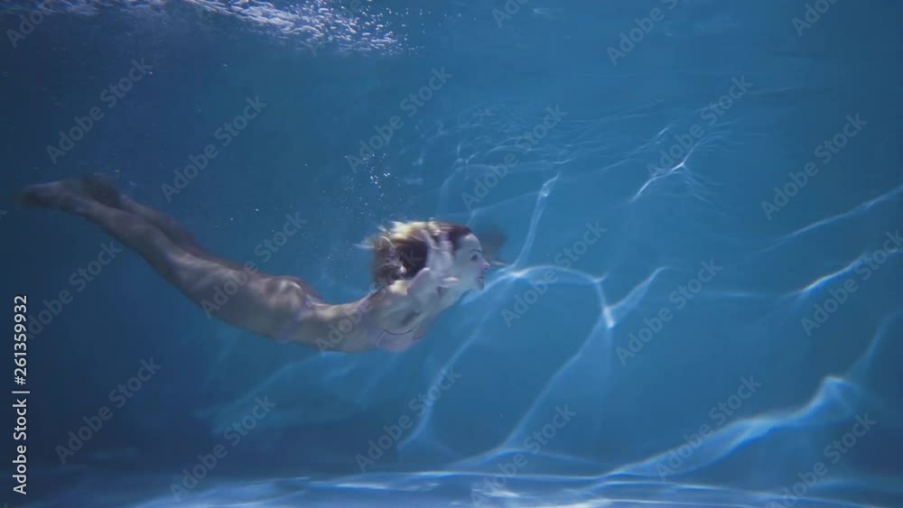 Young woman in lingerie swimming undewater in the swimming pool