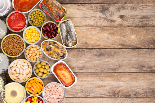 Canned food on wooden background, top view with copy space