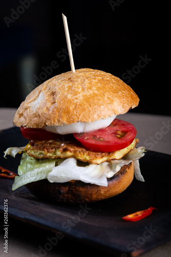 Juicy burger with veal tartar on a wooden scorched board