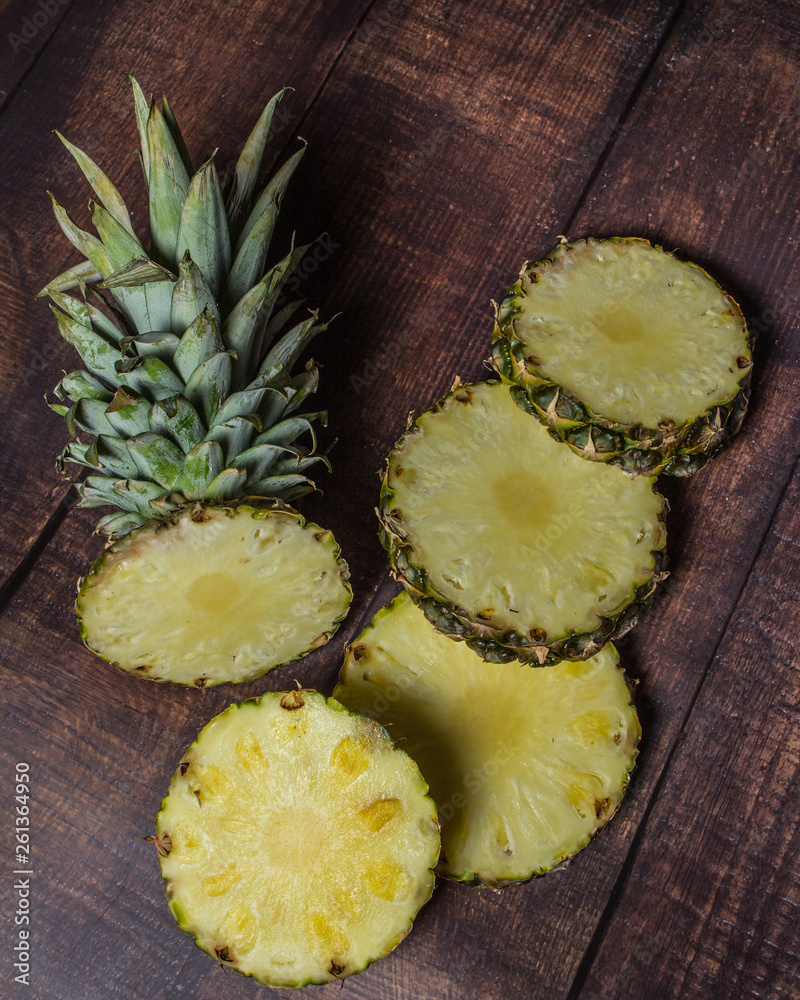 sliced pineapple on a dark board background. Fruit on the kitchen table. sliced pineapple on a dark board background. Fruit on the kitchen table.