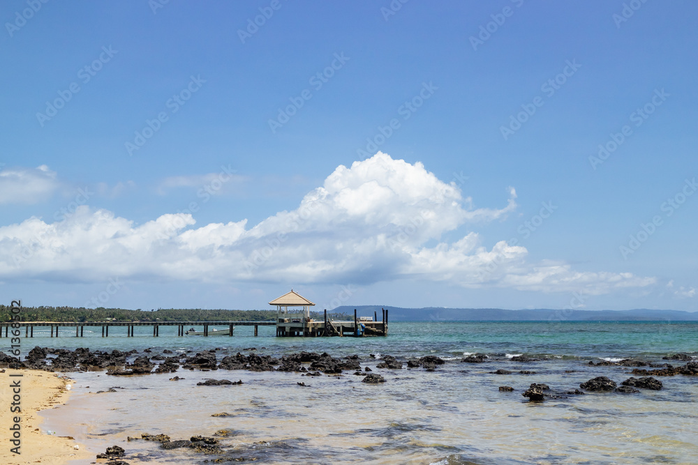 Wooden walkway that leading to the sea from the beach with speed boats and island in background in summer in Koh Mak Island at Trat, Thailand.