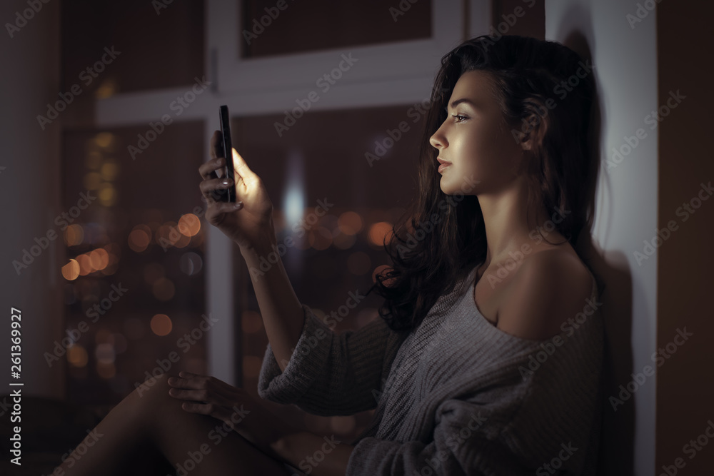 Woman use of mobile phone indoors at night Woman use of mobile phone indoors at night