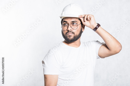 Young builder engineer with glasses and a white protective helmet.