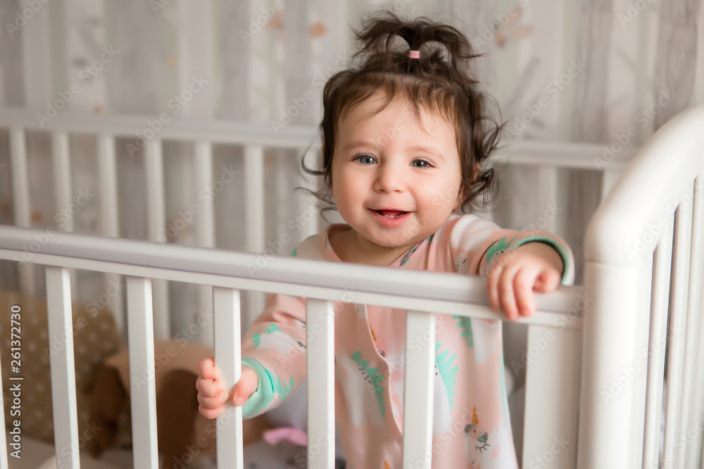 child learns to walk, baby girl in bed smiling, children's room, textiles for children's room child learns to walk, baby girl in bed smiling, children's room, textiles for children's room