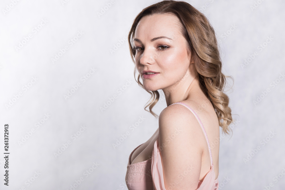 Portrait of beautiful young elegant female in pale pink wedding dress with big neckline, on a white background.