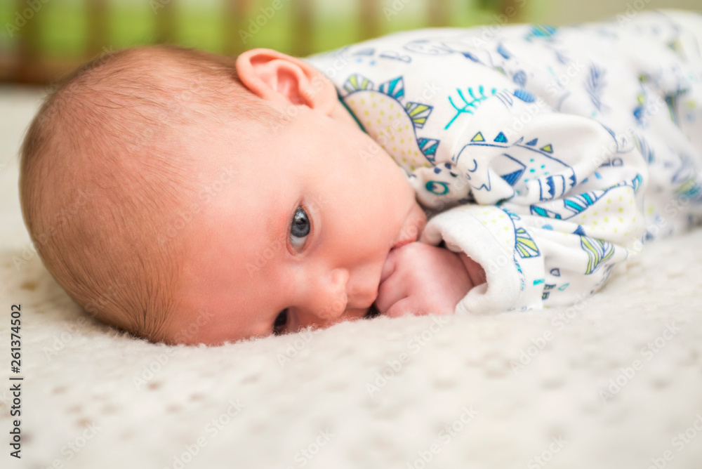 Portrait of a cute baby lying down on a bed. New family and love concept. Happy toddler in bodysuit Portrait of a cute baby lying down on a bed. New family and love concept. Happy toddler in bodysuit
