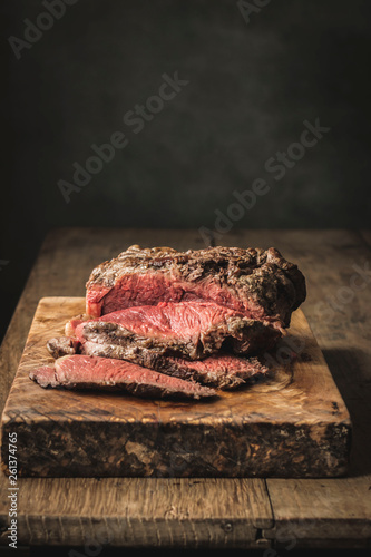 Juicy fresh cooked roast beef on rough cutting board on table photo