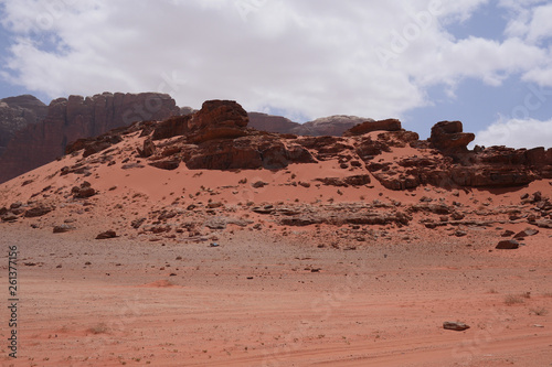 Felslandschaften im roten Wüstensand des Wadi Rum mit Verwehungen an Steinen