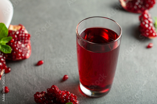 Pomegranate juice in a glass on gray background.