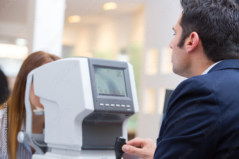 optometrist in exam room with woman in chair optometrist in exam room with woman in chair