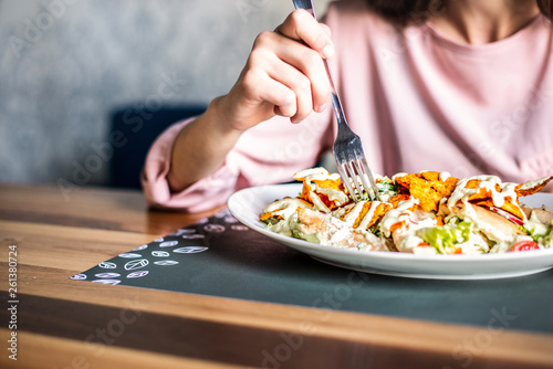 Woman eating at the restaurant, closeup of big mixed salad plate