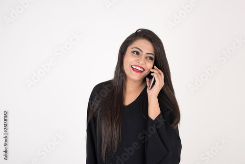 Arab woman in traditional dress using cell phone on white background
