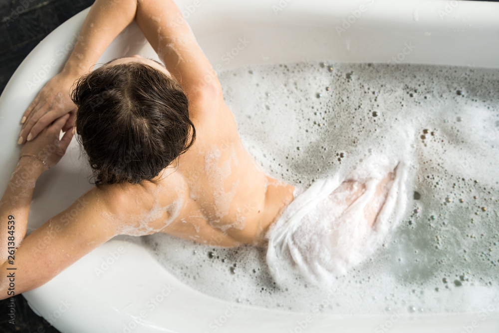 A young attractive girl relaxes in the bathroom and rests against the backdrop of a beautiful light interior. Spa treatments for beauty and health with skin care A young attractive girl relaxes in the bathroom and rests against the backdrop of a beautiful light interior. Spa treatments for beauty and health with skin care