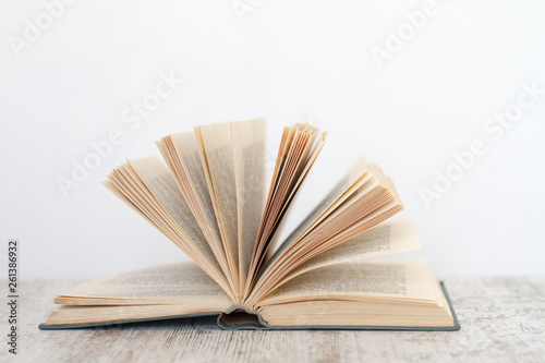 Open book on a wooden surface against the background of a white wall, the concept of education and training.