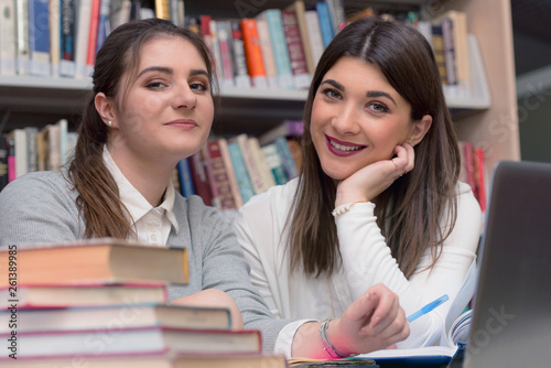 Two Beautiful adult female students spending break at university library. searching for necessary literature lesson. Studying books at the library table.