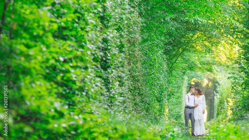 couple in love walking. green tree tunnel and railroad track.