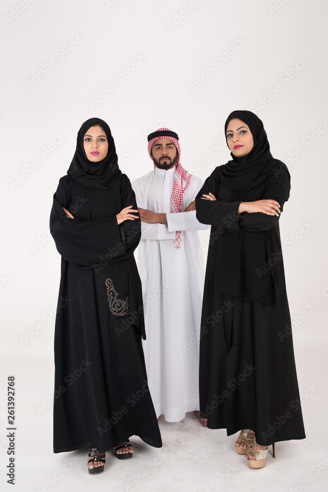 Two arab females with one male smiling and standing on white background Two arab females with one male smiling and standing on white background