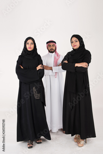 Two arab females with one male smiling and standing on white background