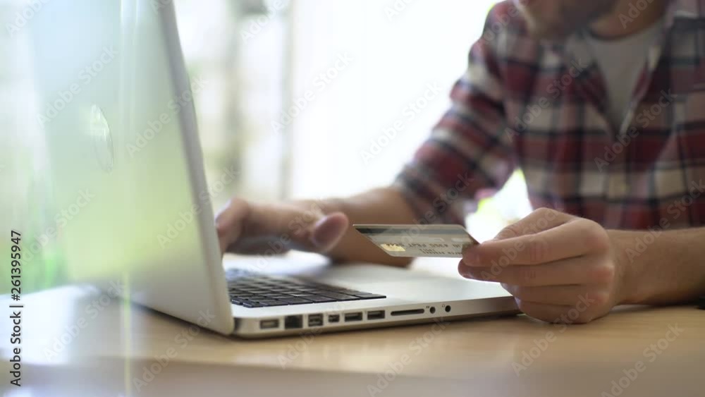 Mid section of young man using a laptop while making online payment through credit card at home