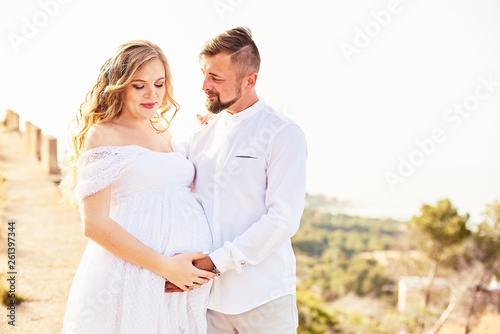 Portrait of a young pregnant woman posing with her husband on a sunny summer day © bodiaphoto