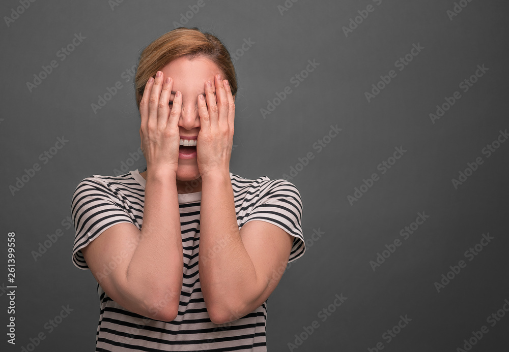 Young woman hides her face on a gray background. Young woman hides her face on a gray background.