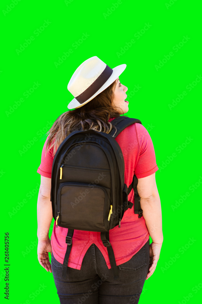 A traveling woman on green background walks away while looking at something to her right A traveling woman on green background walks away while looking at something to her right