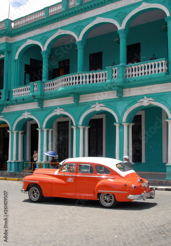 Ville de Santa Clara, vieille voiture américaine orange devant bâtiment vert à arcades et balcon, Cuba, caraïbes