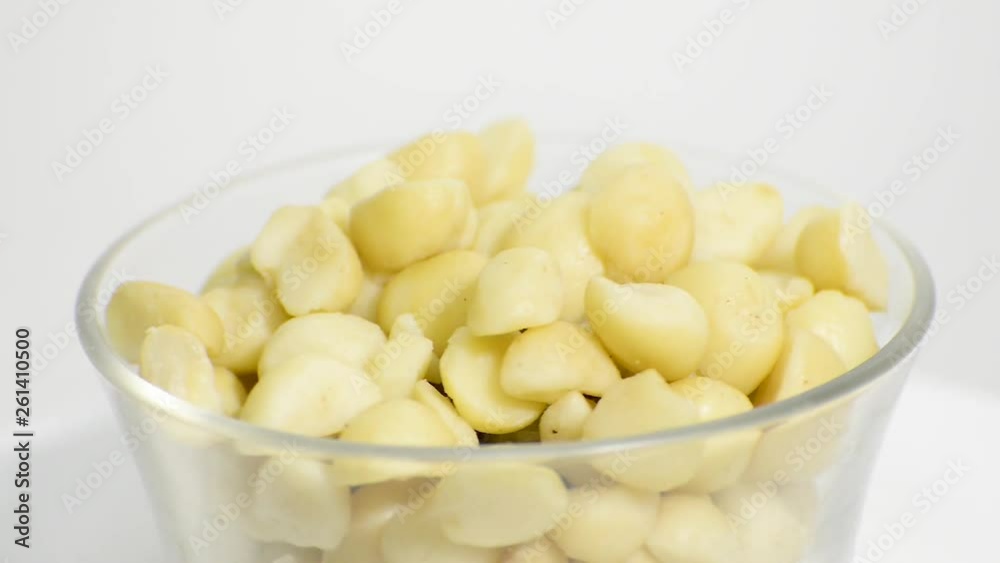 Transparent glass bowl with macadamia nuts rotating on a white background. Flat plane. High angle shot Transparent glass bowl with macadamia nuts rotating on a white background. Flat plane. High angle shot