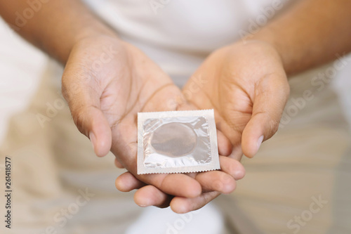 Condom ready to use in female hand, give condom safe sex concept on the bed Prevent infection and Contraceptives control the birth rate or safe prophylactic. World AIDS Day, Leave space for text.