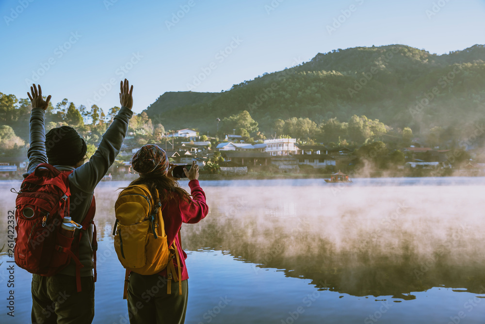 An Asian couple who is standing and watching the fog rising on the lake in the morning. Travel Ban Rak Thai village, Mae Hong Son in Thailand. Take a picture of the lake