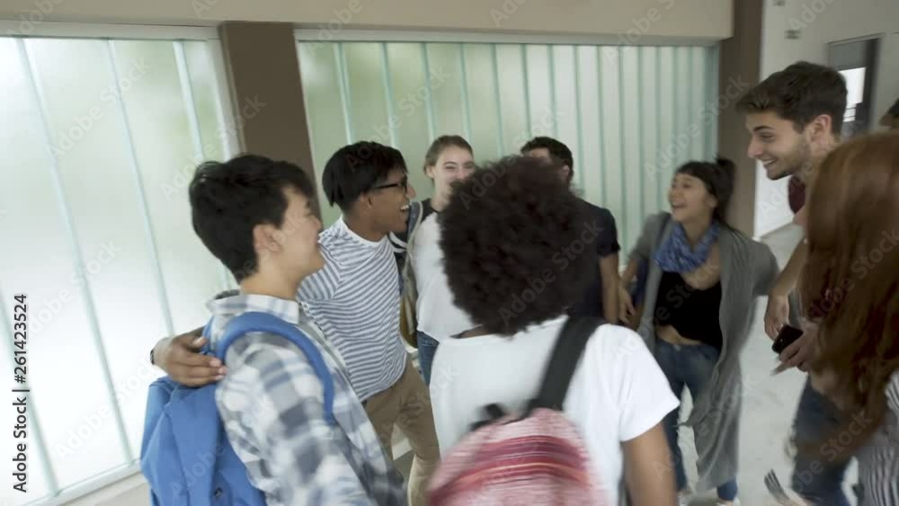 Point of view shot of college students stacking hands together and cheering while standing in college corridor Point of view shot of college students stacking hands together and cheering while standing in college corridor