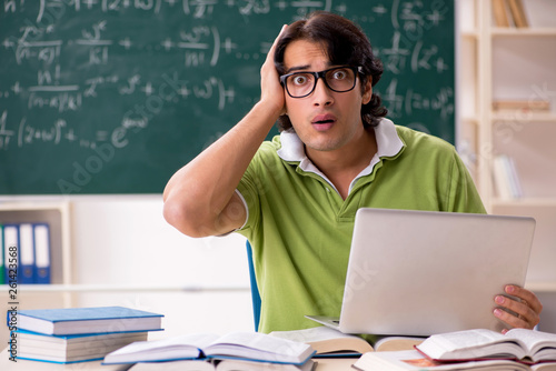 Handsome student in front of chalkboard with formulas 