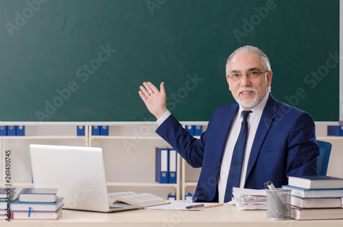 Aged male teacher in front of chalkboard 