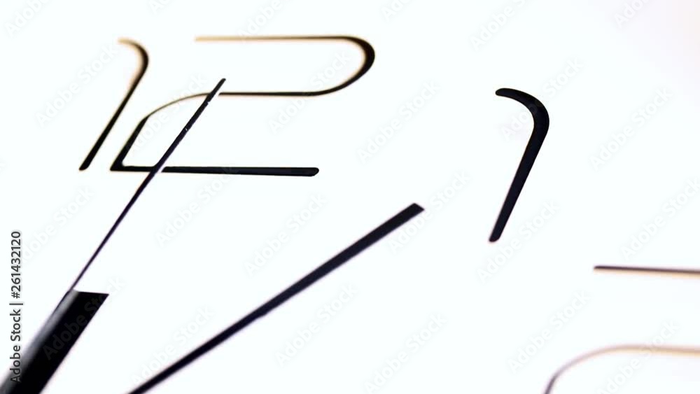 Gradual focusing on the moving second hand in clock. The clock shows five minutes after 12. Gradual focusing on the moving second hand in clock. The clock shows five minutes after 12.