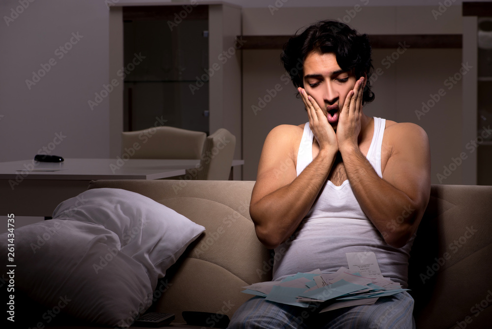 Young man calculating expences night at home Young man calculating expences night at home