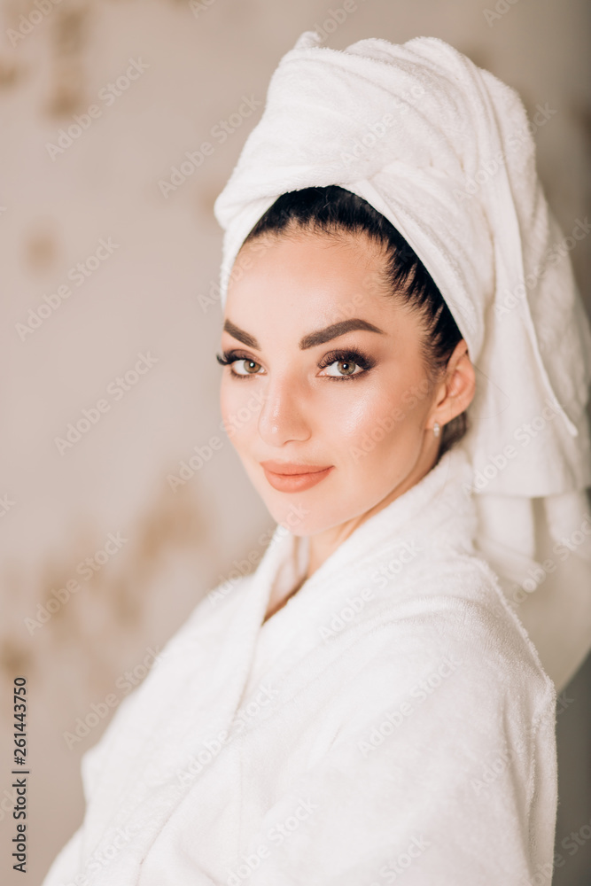 Obraz premium Attractive girl wearing white bathrobe and towel on head in bathroom