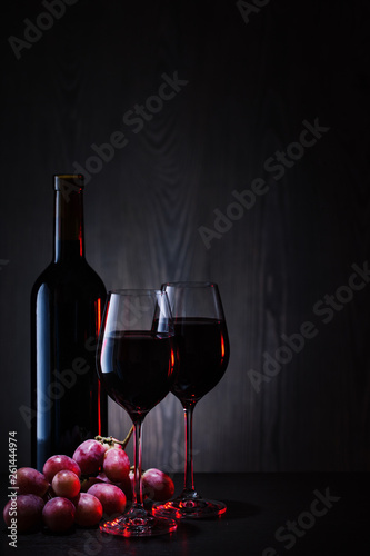 Red wine in glasses and bottle with bunch of red grapes