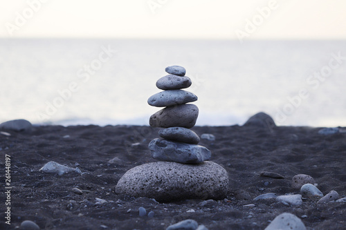 Pyramid of gray stones on the background of the ocean on the beach with black sand in Portugal. Background  texture  close-up  without people  horizontal  plenty of space for text. Nature s concept.