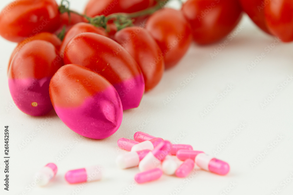 Concept: human GMO manipulation of nature and relative poisoned fruits. Close-up of three tomatoes contaminated by changing color from the medicines in front of it on a white background Concept: human GMO manipulation of nature and relative poisoned fruits. Close-up of three tomatoes contaminated by changing color from the medicines in front of it on a white background